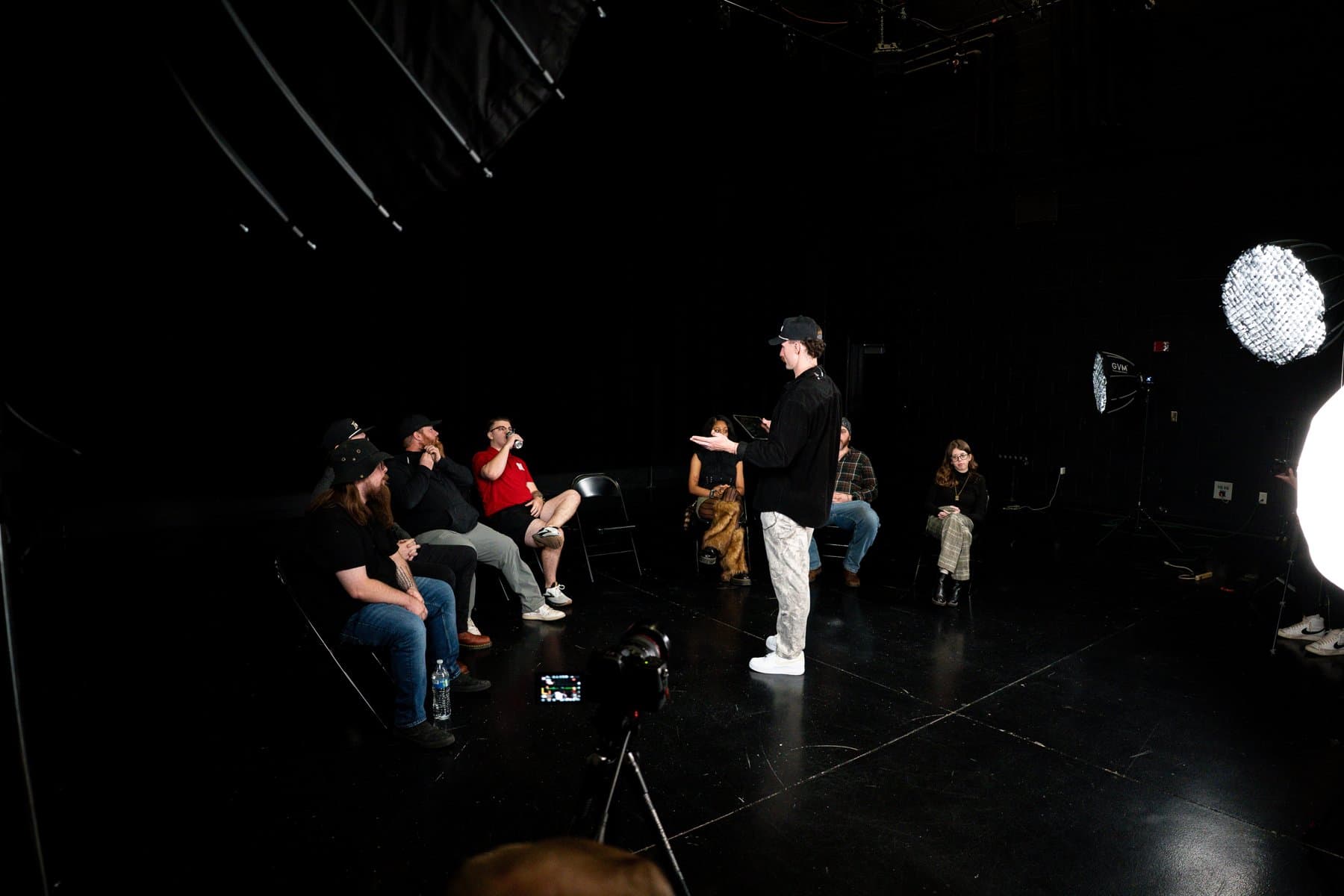 Host briefing the panel before filming, with studio lighting and camera visible